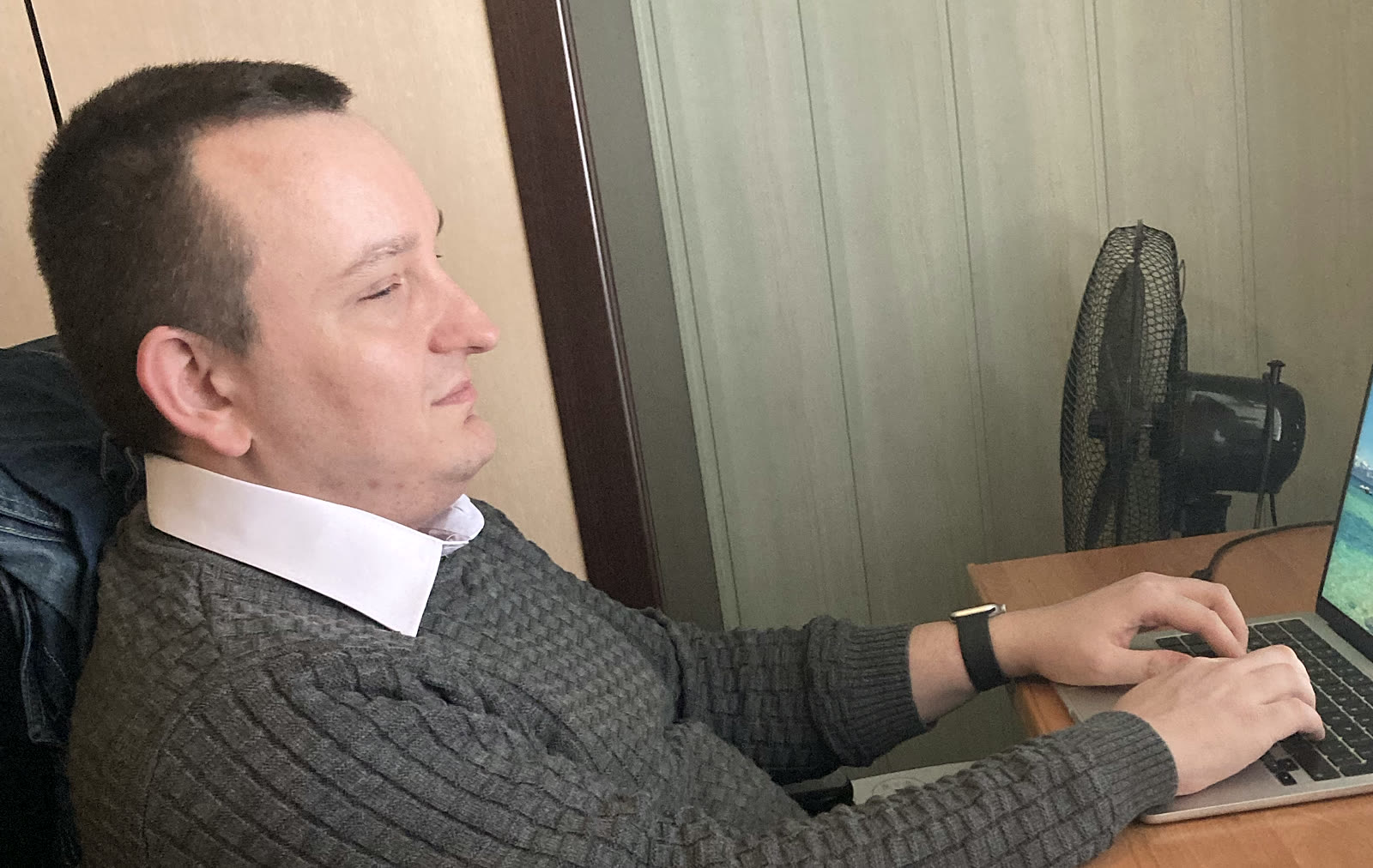 Maciej, skupiony, pracuje na MacBooku z zamkniętymi oczami, bez patrzenia na ekran.